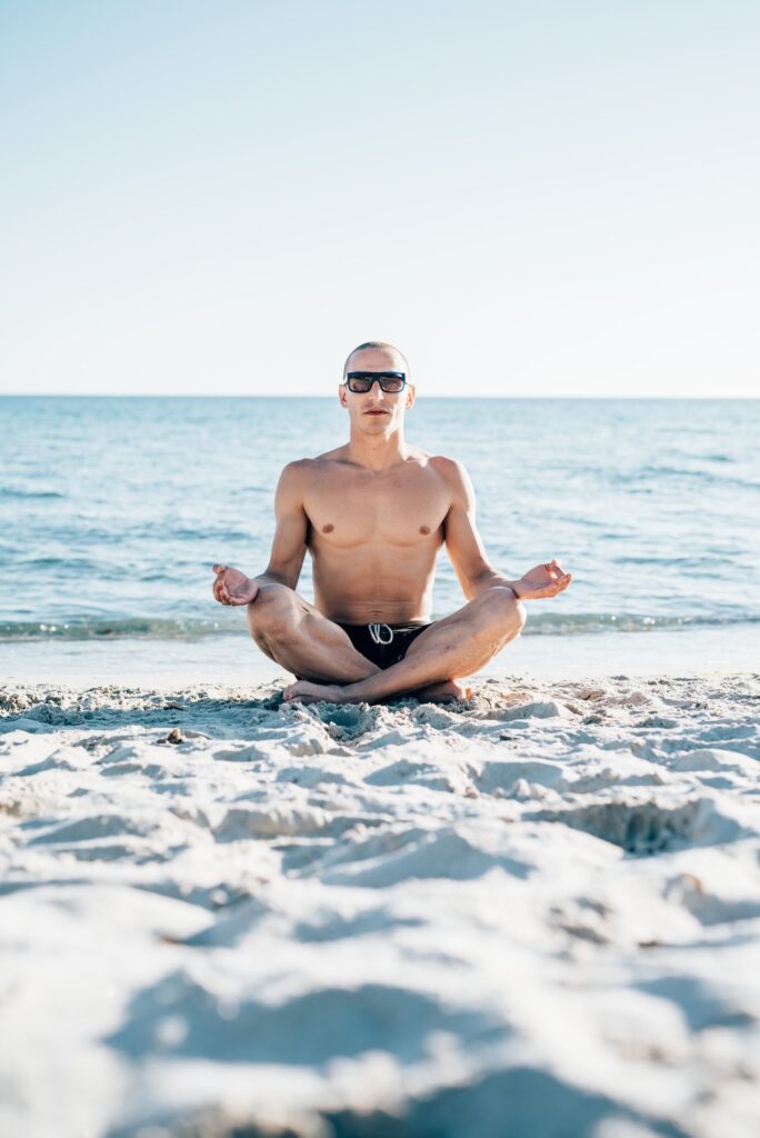 Young man doing yoga at the beach