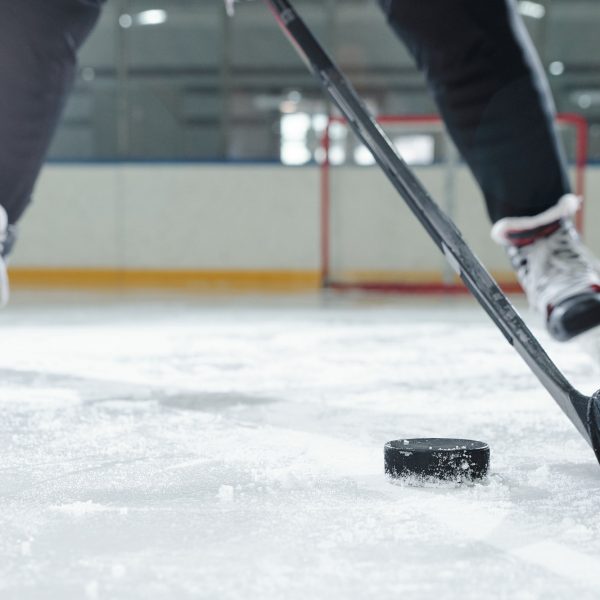 Legs of male hockey player in sports uniform and skates moving down ice rink